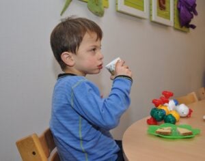 Gutt med fragilt X syndrom drikker fra en kopp