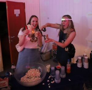 Glade, dansende mennesker drikker brus og spiser popcorn.