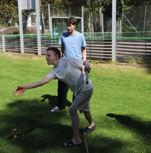 Innbitt gutt spiller kubb på gresset.