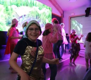 Scenen er full av blide mennesker som danser. Smilende deltaker ser i kamera.