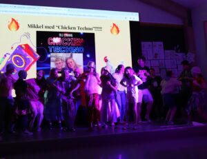 Scenen er full av blide mennesker som danser kyllingdansen.
