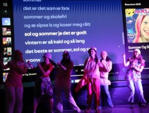 Gruppe mennesker danser og synger på scenen.