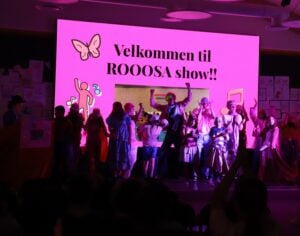 Gruppe mennesker på scenen, ønsker velkommen til Rosa Show.