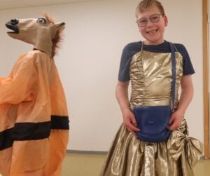 Personer i utkledning. En i sumodrakt med giraff hode. En i gullkjole.