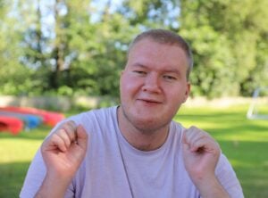 Blid deltaker ser i kamera. Rundt han er det grønt gress, og sola skinner.