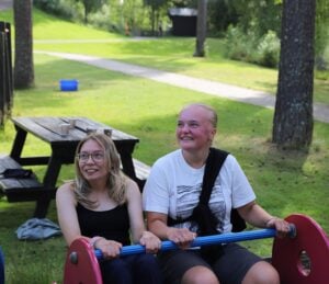 To jenter sitter i en gyngehuske. De smiler og ler.