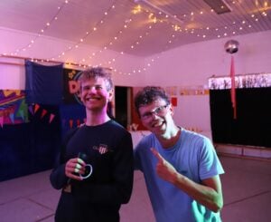 To personer i en lyssatt disco-sal. De smiler og ler.