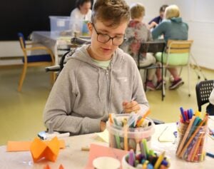 En person sitter ved et bord og tegner.