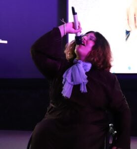 En person sitter på scenen og synger.