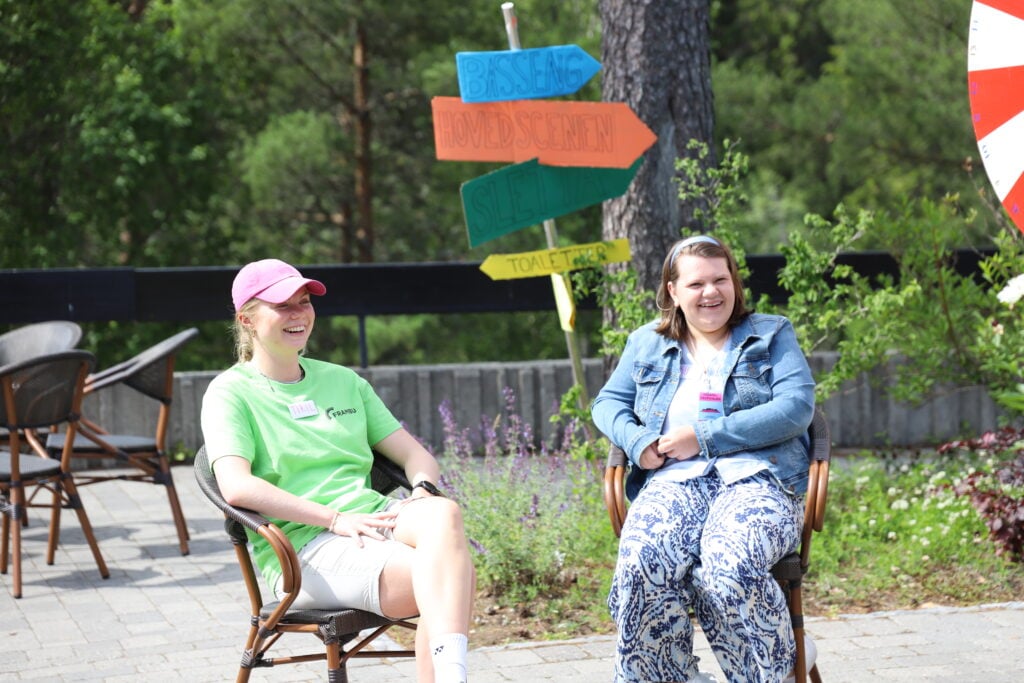 to blide unge damer sitter ute i solen i atriet