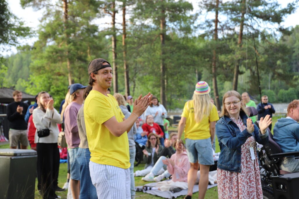 Mange står og sittet på sletta og flere klapper