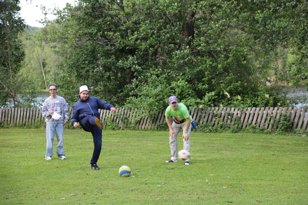 Tre unge menn spiller fotball og en starter et spark