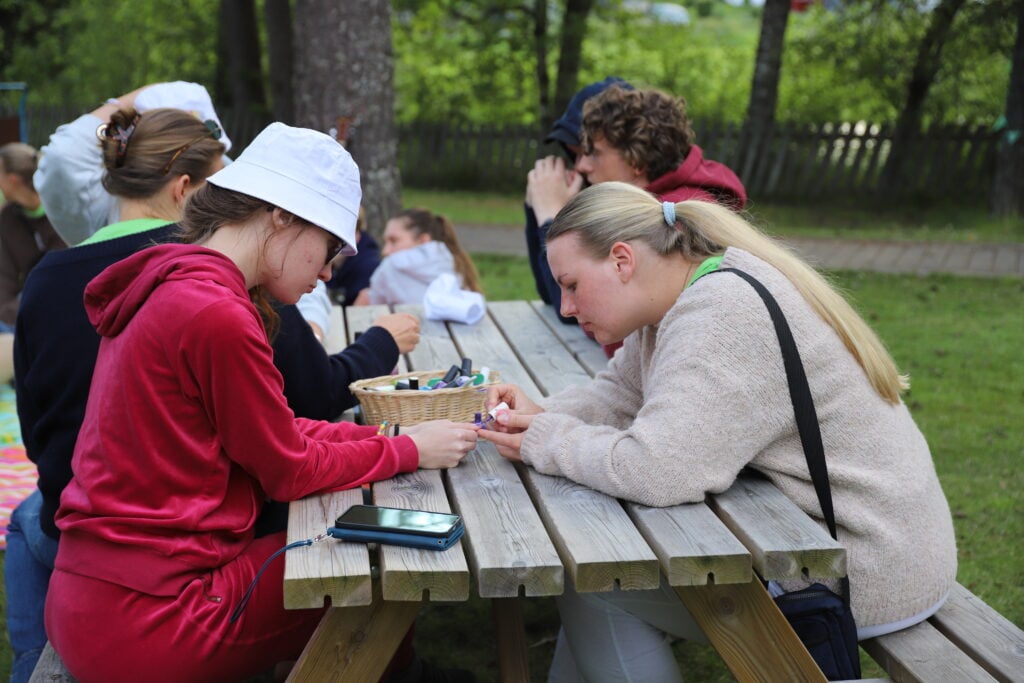 flere sitter på benk på sletta og en får på negllakk