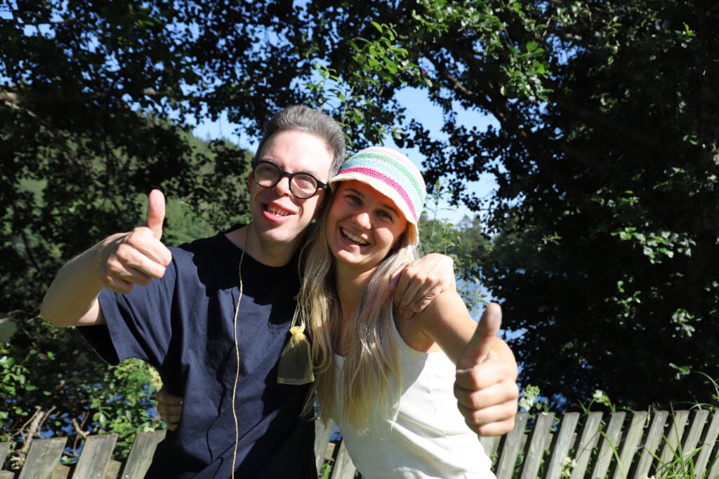 To glade personer med tommel opp på sletta