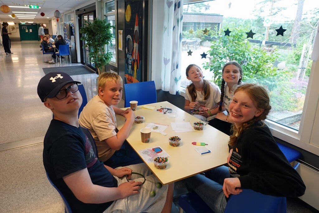 En gruppe sitter og perler i korridoren
