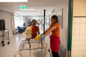 Ung mann og ung kvinne i grønne t-skjorter står foran skilt: Velkommen om bord.